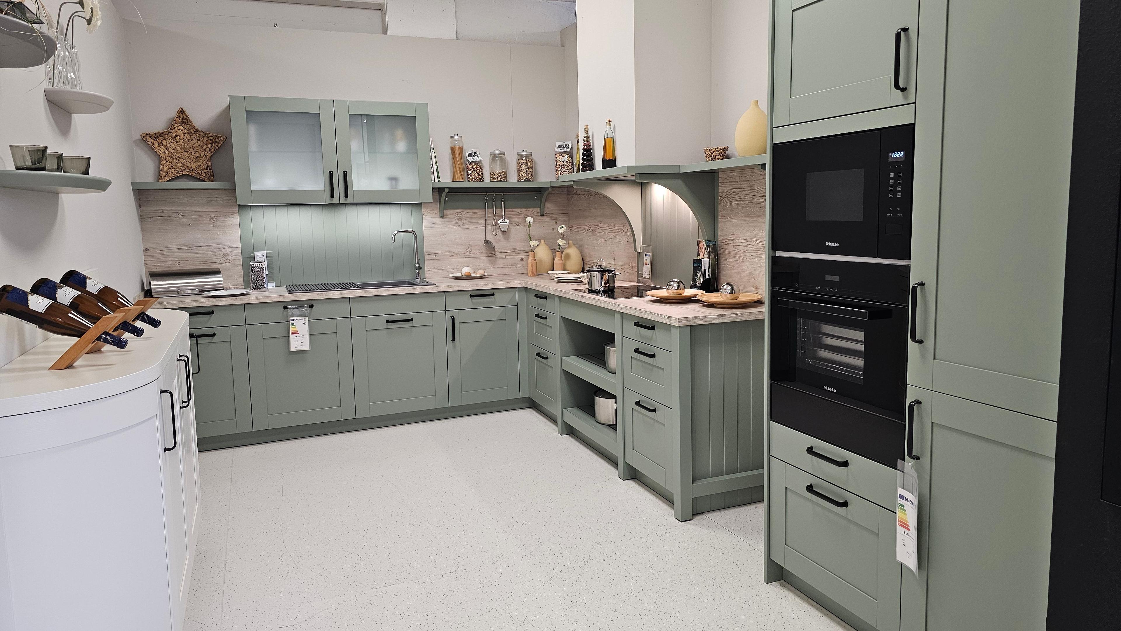 L-förmige Landhausküche in Mintgrün mit offenen Regalen, Holzarbeitsplatte und Miele-Geräten – charmante Küchen in Füssen und dem Allgäu.