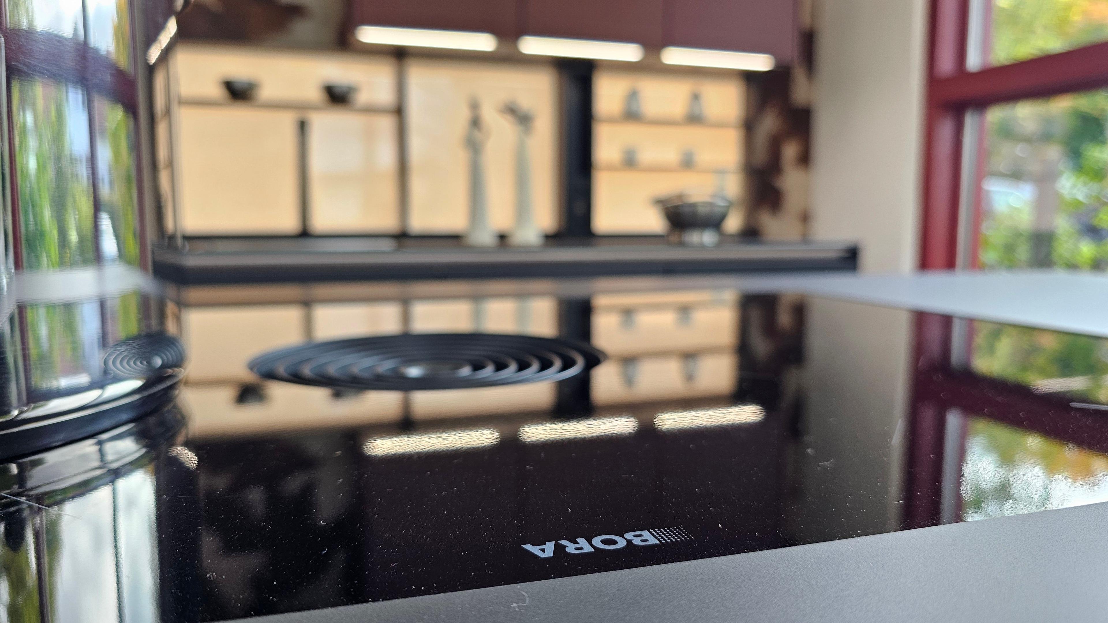 Nahaufnahme eines BORA-Kochfeldes mit integriertem Dunstabzug, dahinter offene Regalwand – innovative Küchentechnik für Küchen in Füssen und dem Allgäu.