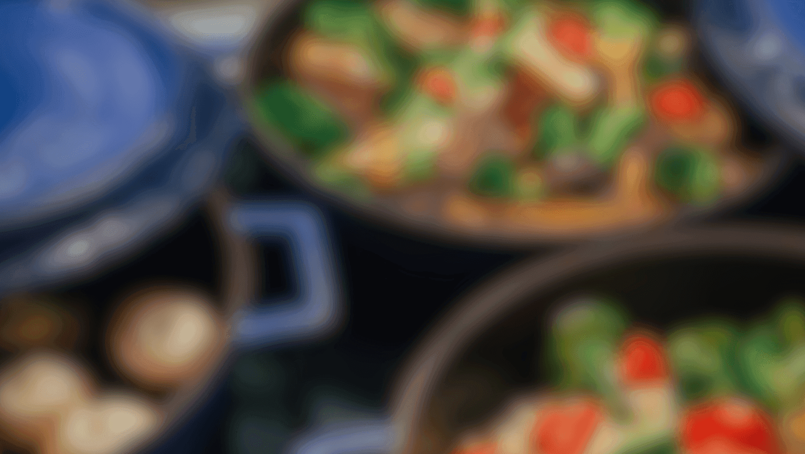 Unscharfes Bild von mehreren Töpfen mit buntem Gemüse und Zutaten, symbolisch für frisch zubereitete Speisen in modernen Küchen in Füssen und dem Allgäu.